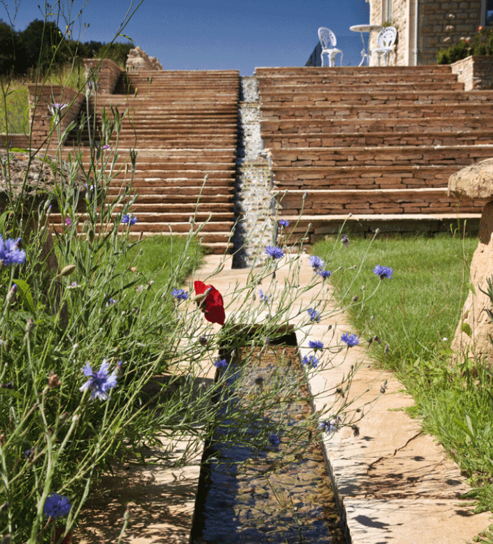 A west-facing terrace with a rill water feature designed by Cotswold Estates and Gardens.