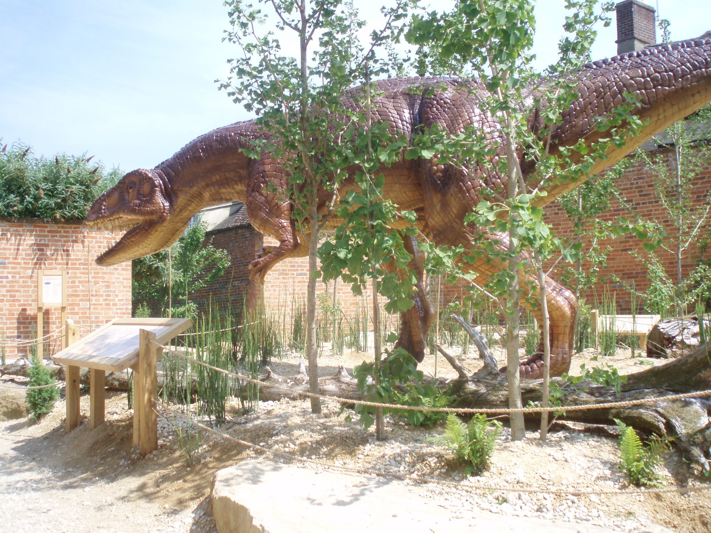 A dinosaur-themed garden featuring dinosaur statues, lush plants, and creative landscaping.