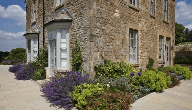 Ebrington House surrounded by beautifully designed plant borders, showcasing the landscaping work by Cotswold Estates and Gardens.