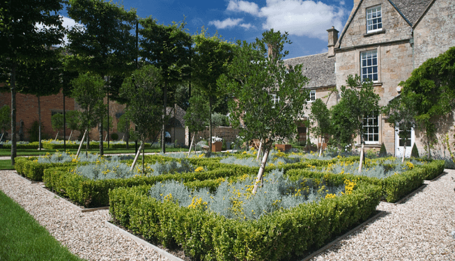 A stone gravel path with squares of plants and hedges, designed by Cotswold Estates and Gardens.