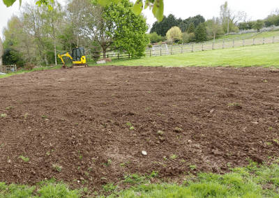 An excavator breaking through compacted soil in the TBC garden, part of project 8063.