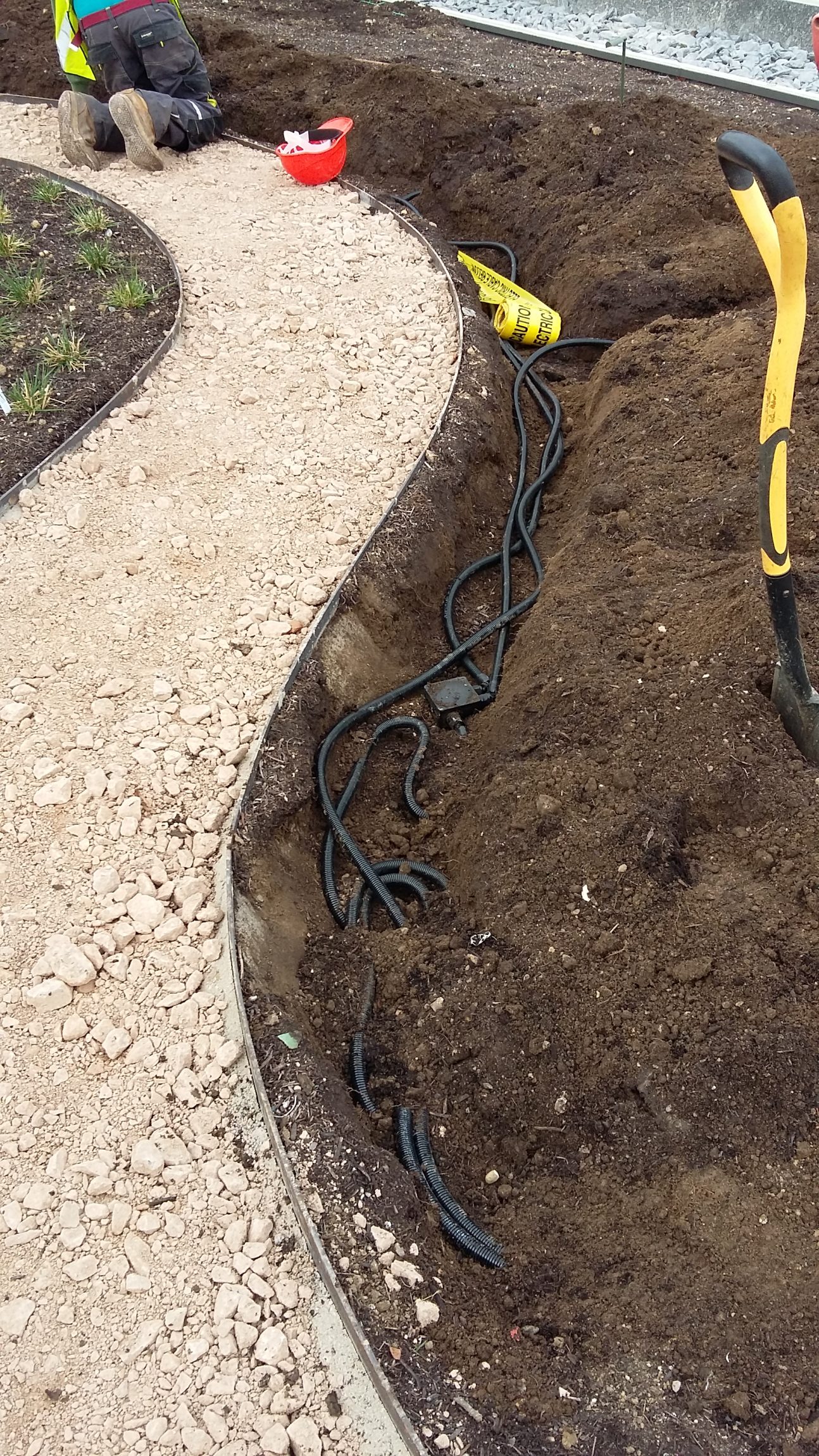 Electric works being installed in a garden, with wiring and electrical components visible.