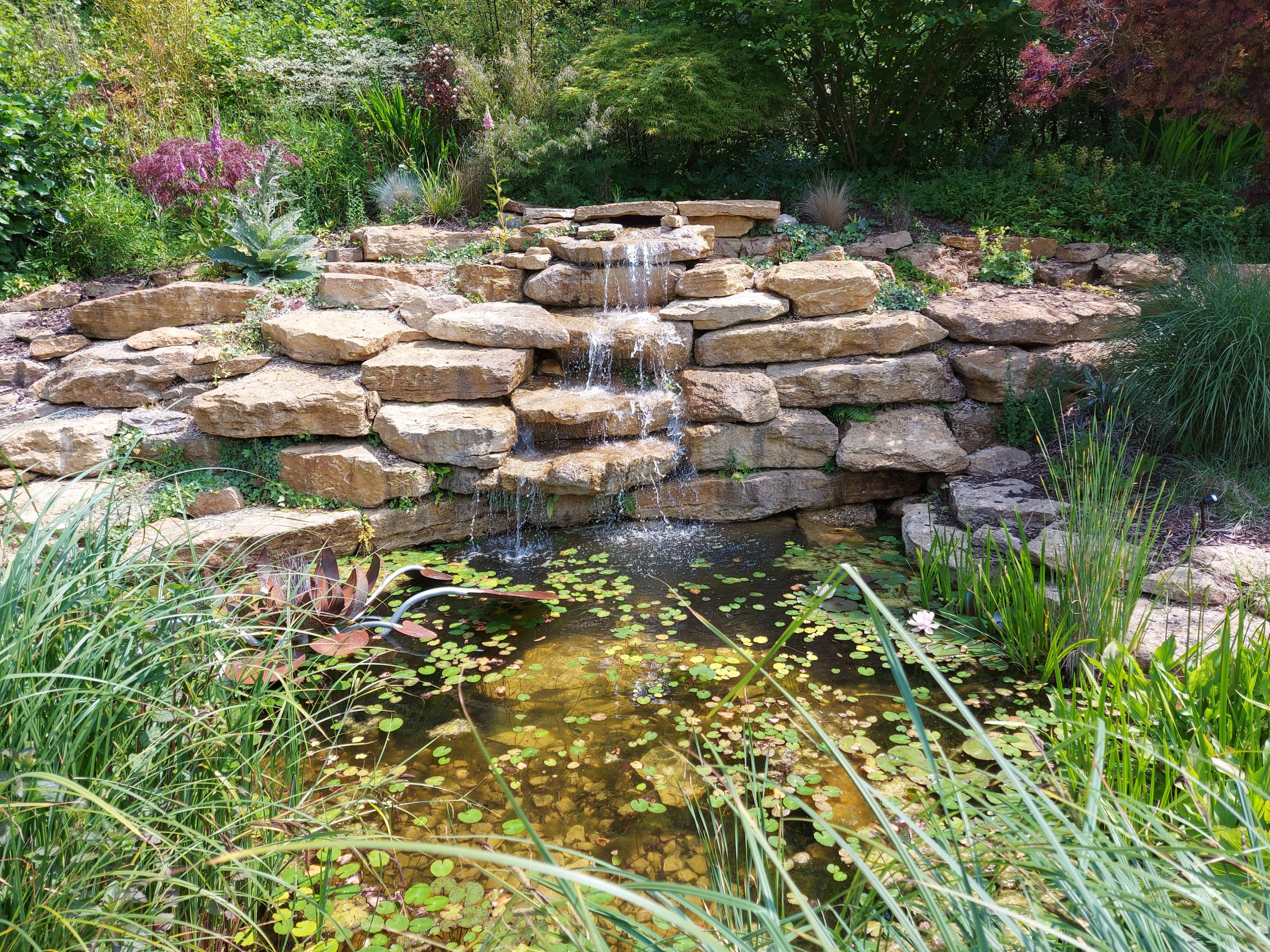 A video of a natural stream created by Cotswold Estates and Gardens, flowing through a landscaped garden.